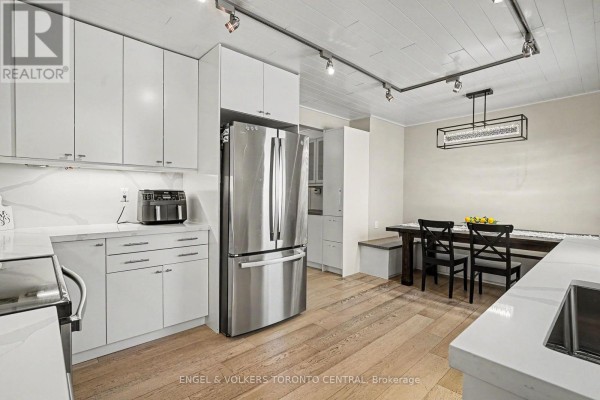 Empty room with light-colored walls, wood flooring, and door leading to staircase - 28 Inverleigh Drive, Toronto