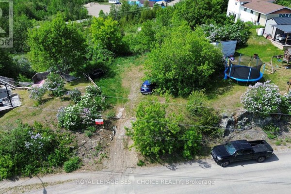 Snow-covered slope with bare bushes and part of a dark structure visible. - 28 Laird Crescent, Cobalt