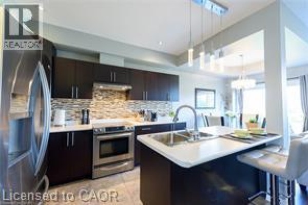 Kitchen with dark cabinets, stainless steel appliances, and island with white countertop. - 28 Madonna Drive, Hamilton