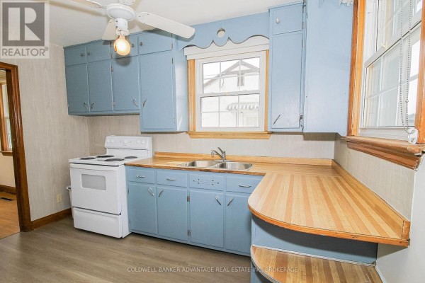 Light blue cabinets, white stove, double sink, butcher block counter - 28 Marshall Avenue Welland