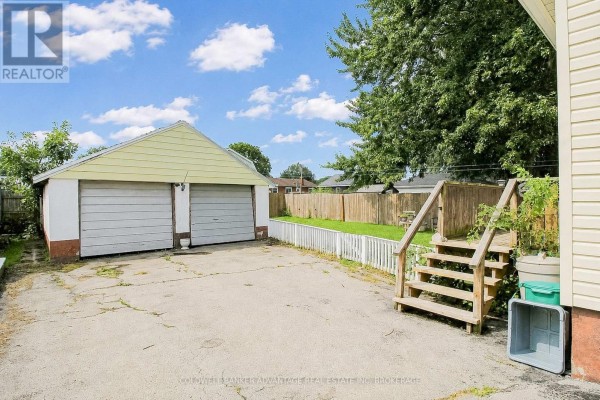 Two-car garage and backyard with fences and deck stairs - 28 Marshall Avenue Welland