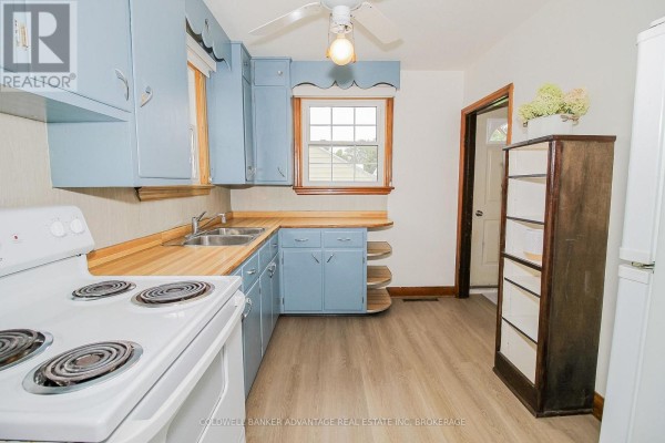 Kitchen with light blue cabinets, white stove, and double sink - 28 Marshall Avenue Welland