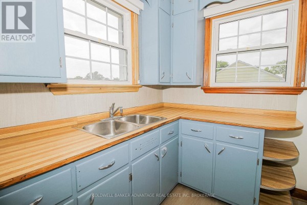 Pale blue cabinets, wood countertops, double sink, and windows in kitchen - 28 Marshall Avenue Welland