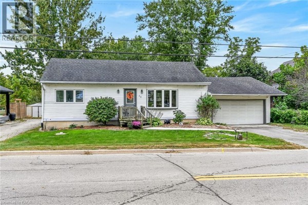 Front exterior of a white bungalow with a single garage door and surrounding trees. - 28 Nelles Street E, York