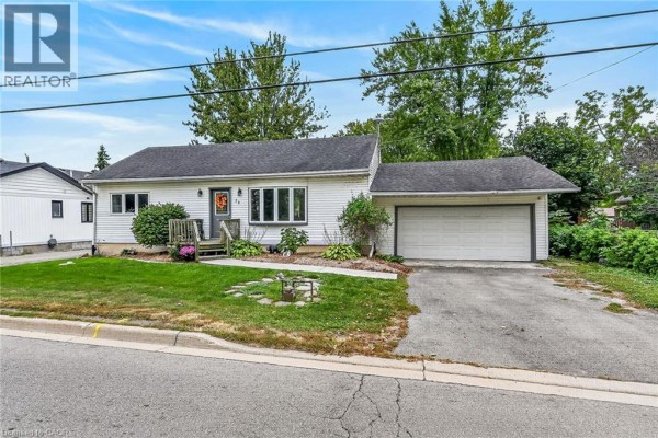 View of the white bungalow exterior showing the front entrance, lawn, and garage. - 28 Nelles Street E, York