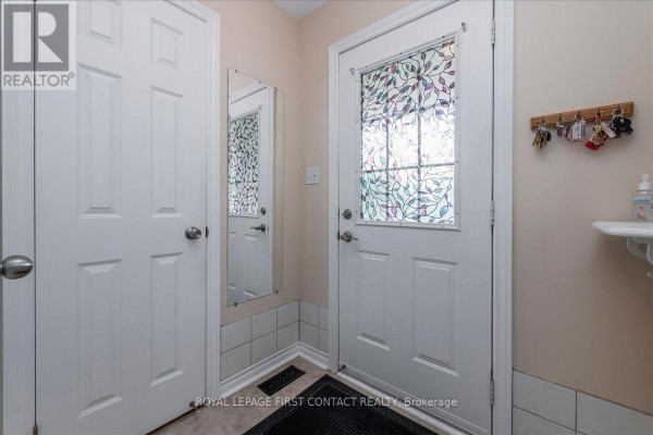 Interior view of a hallway with white doors and a decorative glass entry door. - 28 Pass Court, Barrie