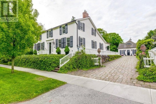 Exterior view of a white home, driveway, and a detached garage or carriage house with a cupola. - 28 Prideaux Street, Niagara On The Lake