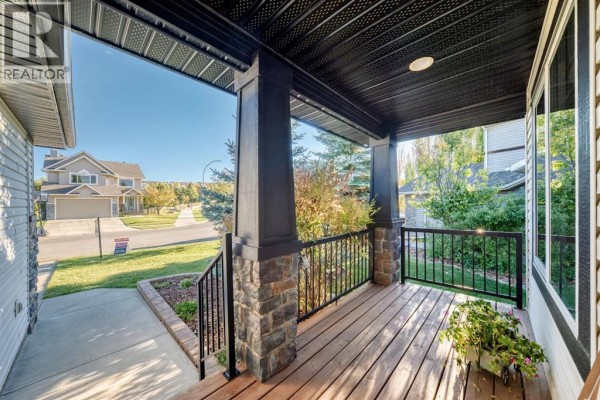 View from a covered front porch showing the street and neighboring houses. - 28 Sheep River Cove, Okotoks