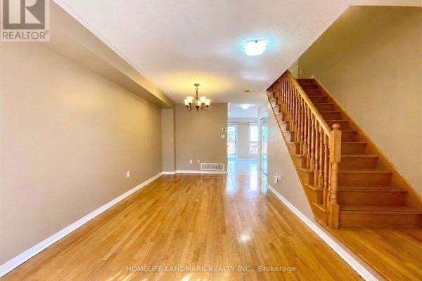 Living room with hardwood floors, beige walls, and wood staircase leading upstairs. - 28 Silver Linden Drive, Richmond Hill