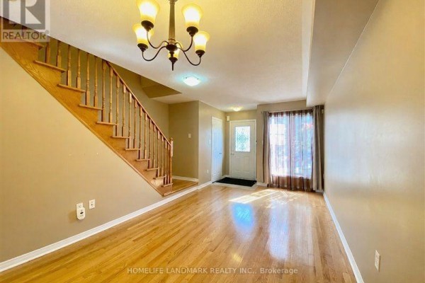 Living room with hardwood floors, beige walls, stairs, front door, and window. - 28 Silver Linden Drive, Richmond Hill