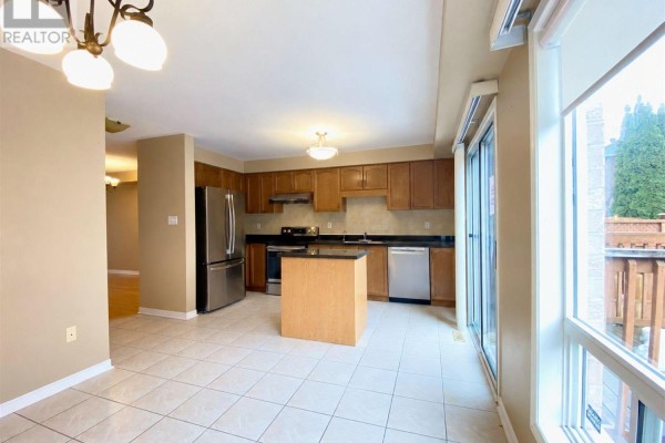 Kitchen with wood cabinets, stainless steel appliances, island, and tiled floor. - 28 Silver Linden Drive, Richmond Hill