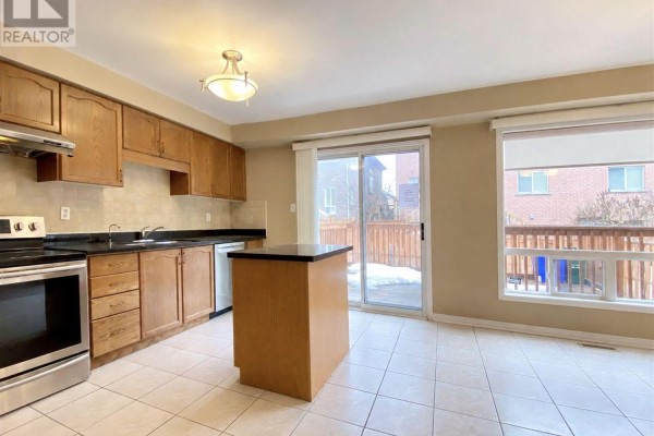 Kitchen with wood cabinets, island, stainless steel appliances, and sliding glass door to deck. - 28 Silver Linden Drive, Richmond Hill
