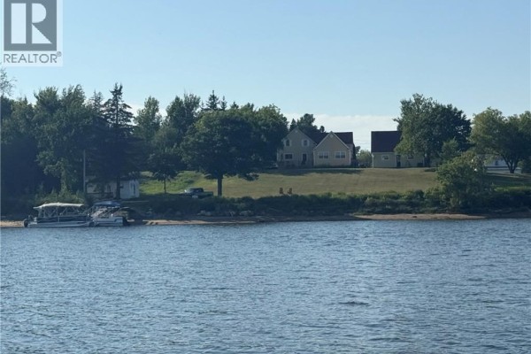 Aerial view of waterfront properties along a wide river with forested shores under a blue sky. - 280 King George Hwy, Miramichi
