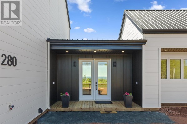 Covered front entrance with double glass doors, black vertical siding, and flower planters. - 280 Lighthouse Road, East Point