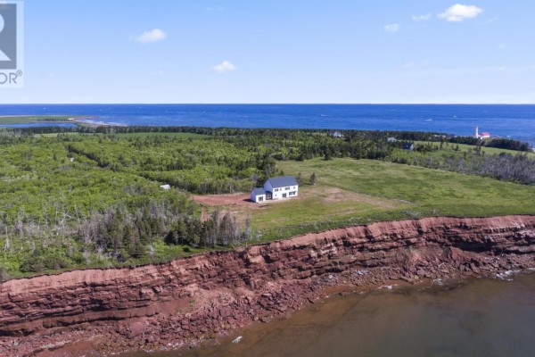 Drone view of house on cliff overlooking ocean with lighthouse in distance. - 280 Lighthouse Road, East Point