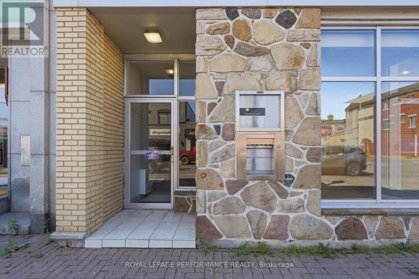 Close-up of the stone facade and entrance with an ATM machine. - 280 Main Street E, Hawkesbury