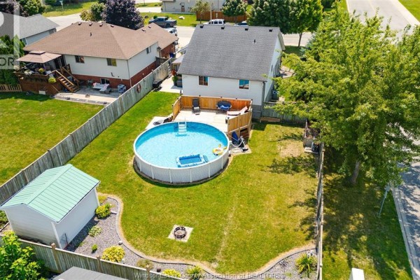 Aerial view of backyard with above-ground pool, wooden deck, shed, and fenced lawn. - 280 Mclellan, Amherstburg