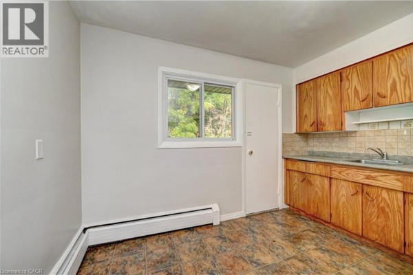 Kitchen area with light wood cabinets, beige tiled backsplash, window, and a white refrigerator. - 280 Sydney Street S Unit# A6, Kitchener