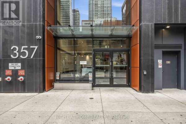 Exterior entrance of apartment building 357 King Street West with glass doors and dark stone facade. - 2801 - 357 King Street W, Toronto
