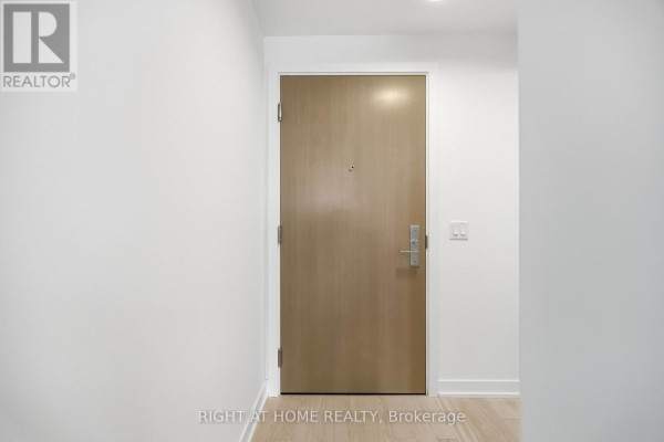 Interior view of a closed light wood apartment door with brushed metal hardware and white walls. - 2801 - 357 King Street W, Toronto