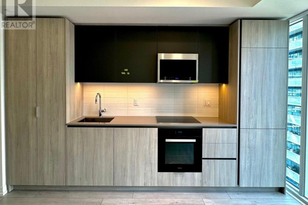 Contemporary kitchen with light wood cabinetry and black accents. - 2802 - 400 King Street W, Toronto