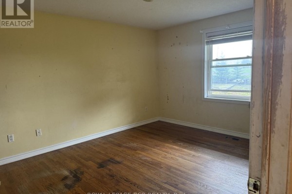 Empty room with yellow walls, hardwood floors, and a single window with white blinds. - 280355 Artemesia-southgate Townline, Grey Highlands