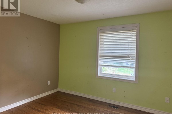 Empty room with one brown wall and one lime green wall, hardwood floors, and a window. - 280355 Artemesia-southgate Townline, Grey Highlands