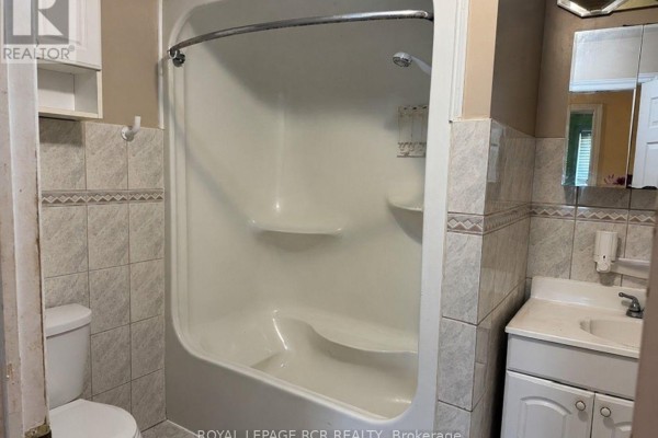 Small bathroom with a white tub, toilet, white vanity with sink, and tiled walls. - 280355 Artemesia-southgate Townline, Grey Highlands