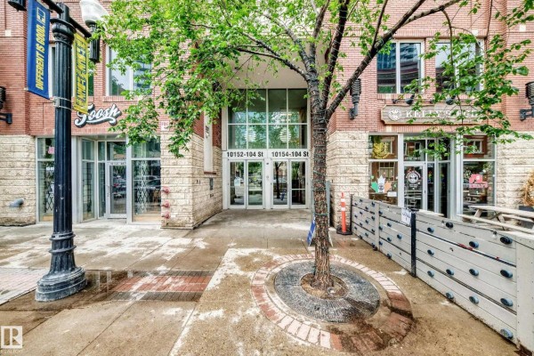Building entrance with glass doors, trees, and decorative stone walls. - #2804 10152 104 St Nw, Edmonton