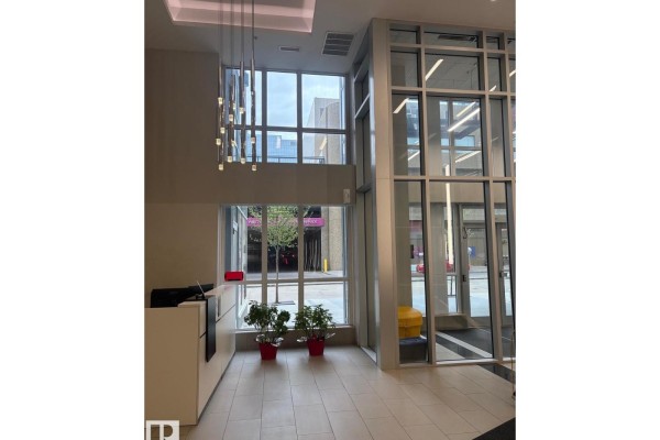 Rooftop patio with tile flooring, glass railings, and seating overlooking a stadium and city. - #2804 10238 103 St Nw, Edmonton