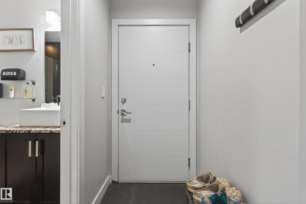 Laundry closet with stacked white front-load washer and dryer and white paneled door. - #2804 10238 103 St Nw, Edmonton