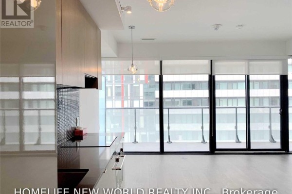 Contemporary kitchen with light wood cabinets, dark countertop, and a glass sliding door. - 2805 - 161 Roehampton Avenue, Toronto