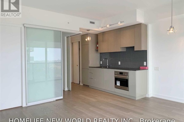 Interior view of apartment kitchen and living area with light wood cabinetry and sliding doors. - 2805 - 161 Roehampton Avenue, Toronto