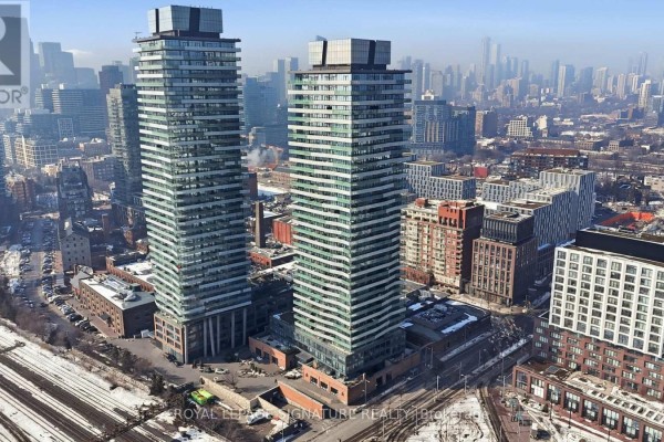 Aerial view of two modern condo towers with glass facades, surrounded by cityscape and distant skyline. - 2805 - 390 Cherry Street, Toronto