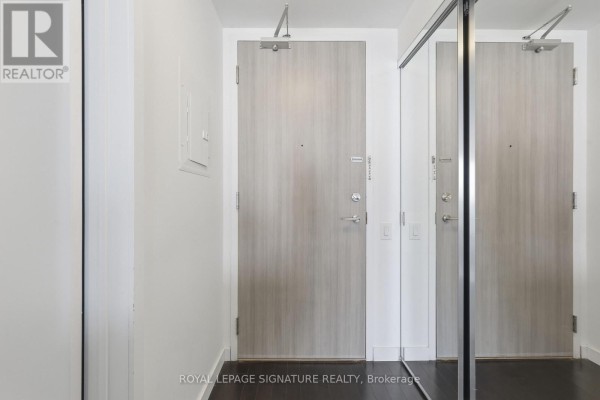 Apartment entrance with light wood doors and a large mirrored closet reflecting the hallway. - 2805 - 390 Cherry Street, Toronto