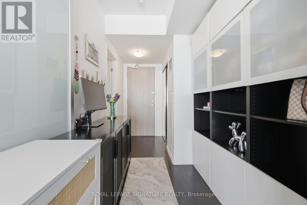 Hallway featuring a long black credenza, floor-to-ceiling white cabinets with glass fronts, and dark wood flooring. - 2805 - 390 Cherry Street, Toronto