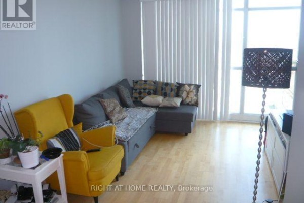 Living room with a grey sectional sofa, yellow armchair, and floor-to-ceiling windows with vertical blinds. - 2807 - 18 Yonge Street, Toronto