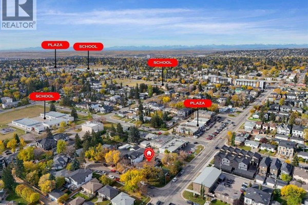 Aerial view of the neighborhood showing schools, plazas, and distant mountains. - 2807 32 Street Sw, Calgary