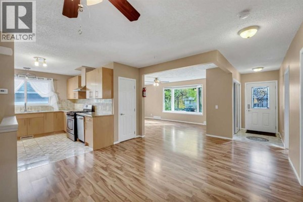 Open concept living area with light wood floors, beige walls, and kitchen. - 2807 32 Street Sw, Calgary