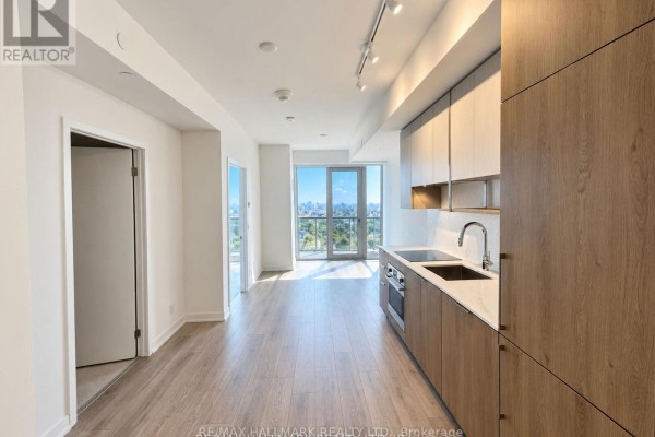 View from an apartment showing a modern kitchen, living area, balcony, and city skyline. - 2809 - 15 Holmes Avenue, Toronto