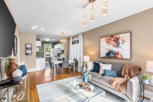 Open concept living room and dining area with grey sofa, glass coffee table, and white dining set. - 281 Lansdowne Avenue, Winnipeg