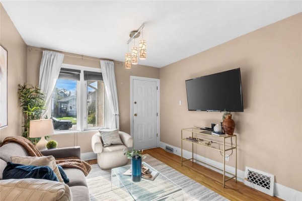 Living room with beige walls, sofa, glass coffee table, and a mounted television on the wall. - 281 Lansdowne Avenue, Winnipeg