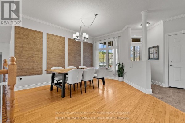 Dining room with a wooden table, white chairs, and large windows. - 281 Topaze Crescent, Clarence Rockland