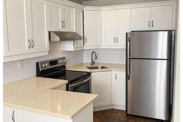 U-shaped kitchen with white cabinetry, beige countertops, stainless steel appliances, and white subway tile backsplash. - 2810 - 40 Homewood Avenue, Toronto