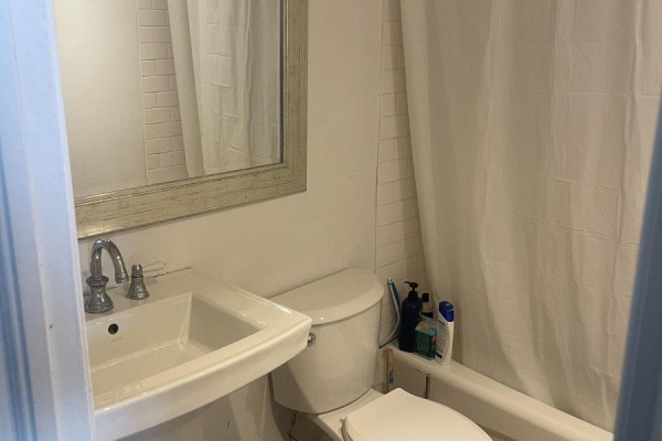 Apartment bathroom with a white sink, toilet, bathtub with shower curtain, and a mirror above the sink. - 2810 - 40 Homewood Avenue, Toronto