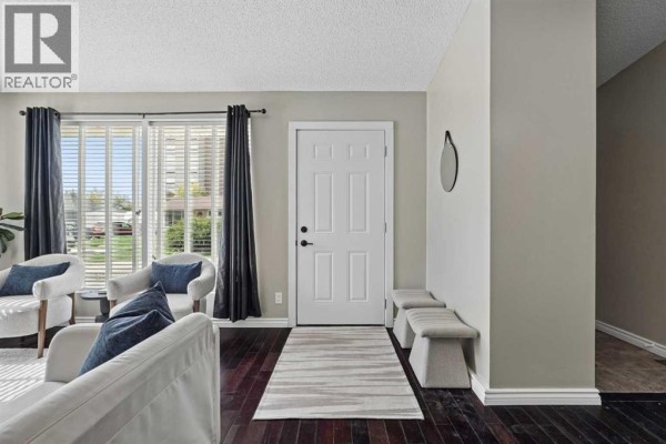 Entranceway inside the home with dark wood floors, a white door, and seating benches. - 2811 13 Avenue S, Lethbridge