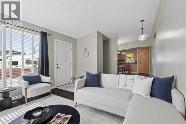 Living room with a sectional sofa, coffee table, large window with a view to the street. - 2811 13 Avenue S, Lethbridge