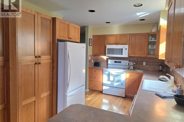 Hallway with wooden doors, light green walls, and access to kitchen - 2813 Clifftop Lane, Whistler