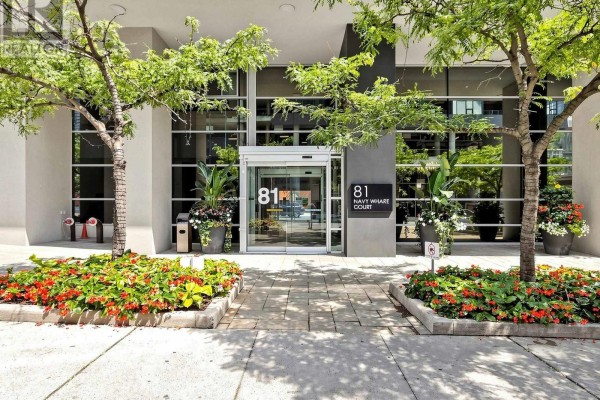 Entrance to 81 Navy Wharf Court building with trees, flowers, and glass doors. - 2815 - 81 Navy Wharf Court, Toronto