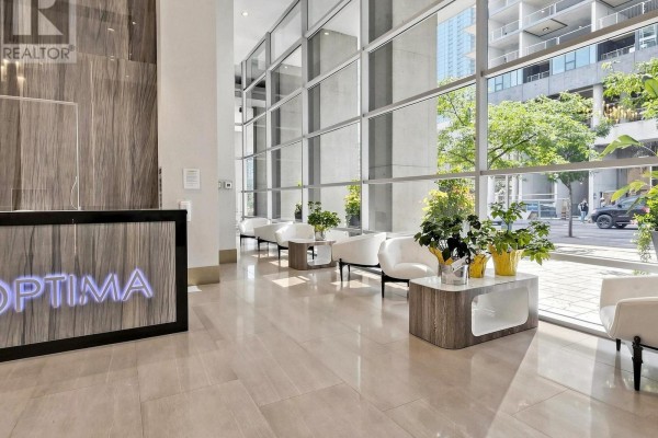 Building lobby with a reception desk, white chairs, coffee tables, and large windows. - 2815 - 81 Navy Wharf Court, Toronto